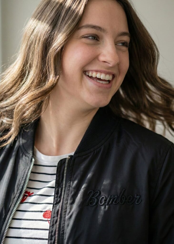 close-up of smiling woman wearing a black bomber jacket over a striped T-shirt
