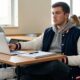 student in bomber jacket outfit sitting in college classroom